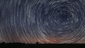 Due to Earth's rotation, the sun, moon, and stars appear in different places in the sky each day. Here, the apparent motion of the stars results in a unique glow across the night sky.