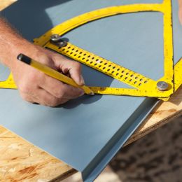 person drawing a line at a specific angle using large protractor