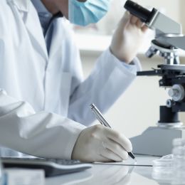 scientist looking into a microscope to study a sample