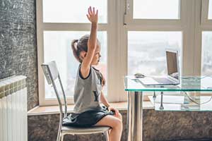 Little girl raising her hand during a remote learning class